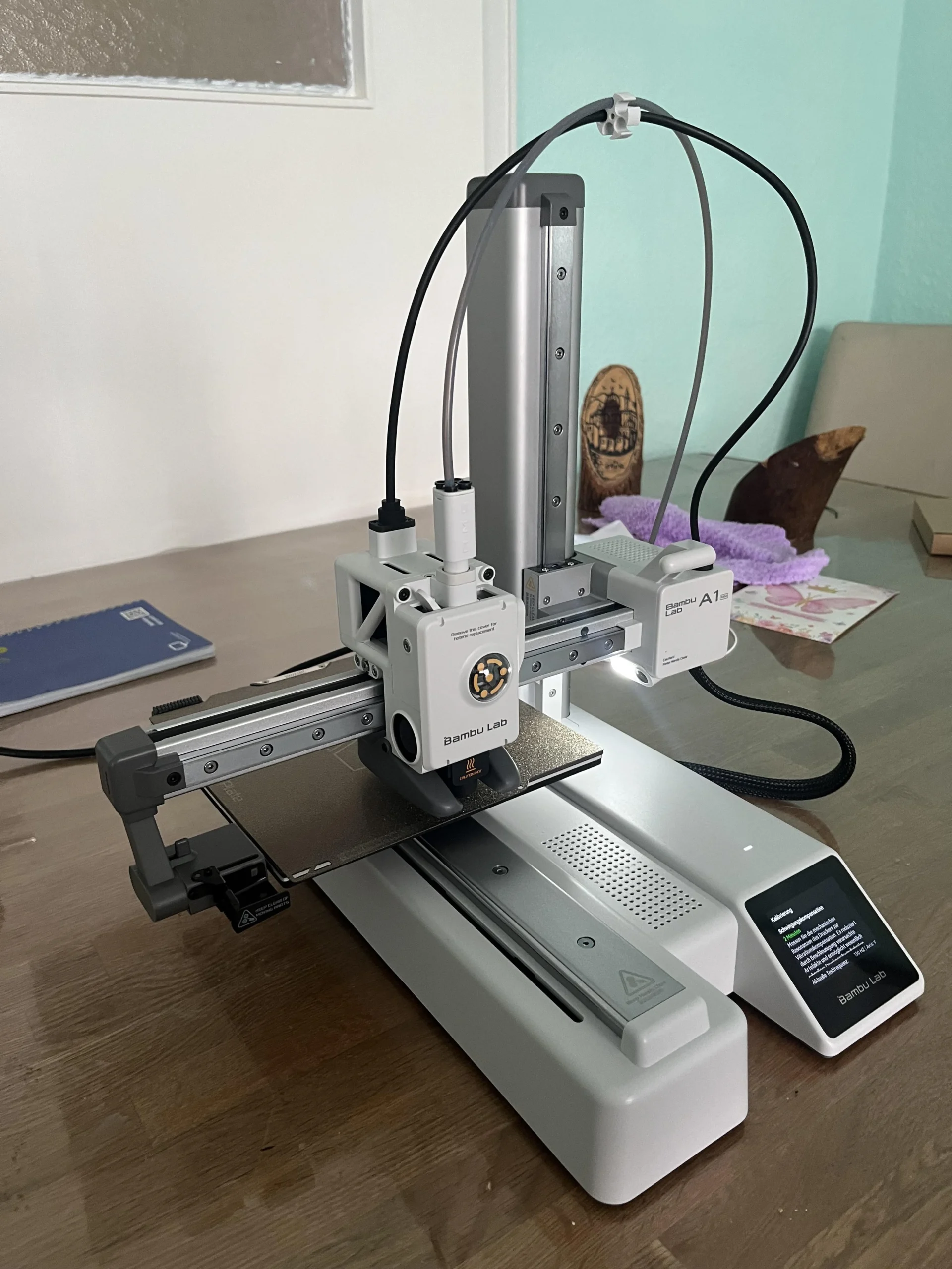 Bambu Lab A1 Mini 3D printer on a wooden workshop desk mid-print